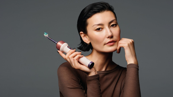 A model poses with the new Dyson CameraJet tootbrush in the rose gold color.
